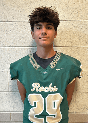 A young man wearing a white and black jersey with the number 14 on it. Description generated by AI