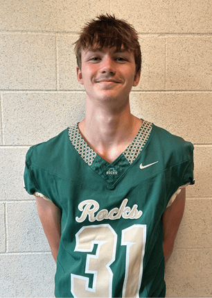 A young man wearing a white and black jersey with the number 14 on it. Description generated by AI