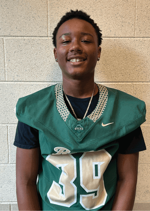 A young man wearing a white and black jersey with the number 14 on it. Description generated by AI