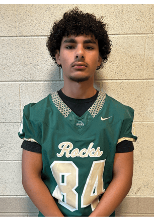 A young man wearing a white and black jersey with the number 14 on it. Description generated by AI
