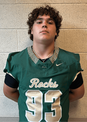 A young man wearing a white and black jersey with the number 14 on it. Description generated by AI