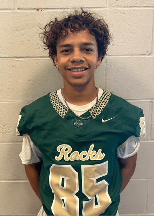 A young man wearing a white and black jersey with the number 14 on it. Description generated by AI