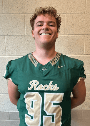 A young man wearing a white and black jersey with the number 14 on it. Description generated by AI