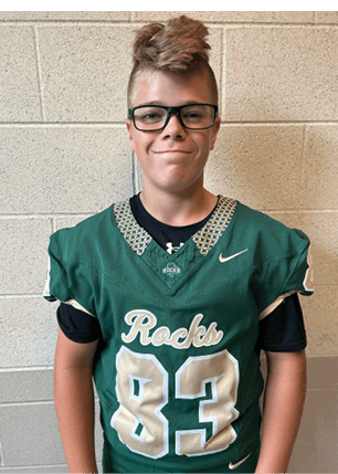 A young man wearing a white and black jersey with the number 14 on it. Description generated by AI