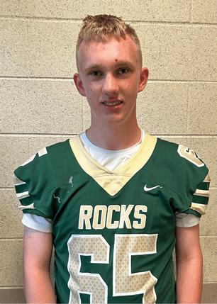 A young man wearing a white and black jersey with the number 14 on it. Description generated by AI