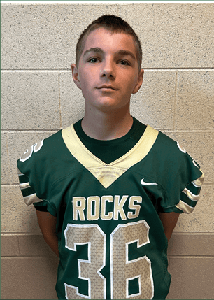 A young man wearing a white and black jersey with the number 14 on it. Description generated by AI
