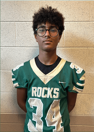 A young man wearing a white and black jersey with the number 14 on it. Description generated by AI