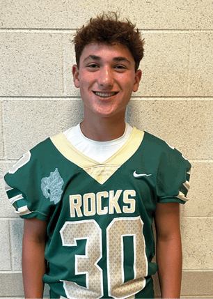 A young man wearing a white and black jersey with the number 14 on it. Description generated by AI