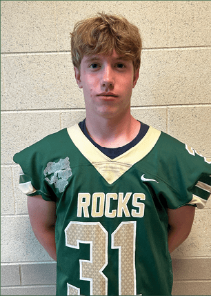 A young man wearing a white and black jersey with the number 14 on it. Description generated by AI