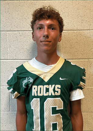 A young man wearing a white and black jersey with the number 14 on it. Description generated by AI