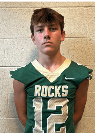 A young man wearing a white and black jersey with the number 14 on it. Description generated by AI