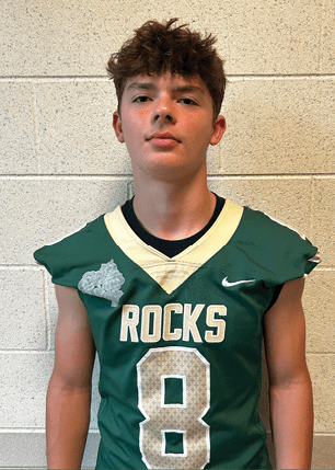 A young man wearing a white and black jersey with the number 14 on it. Description generated by AI