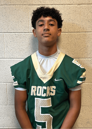 A young man wearing a white and black jersey with the number 14 on it. Description generated by AI