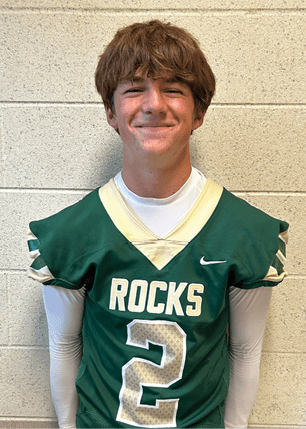 A young man wearing a white and black jersey with the number 14 on it. Description generated by AI