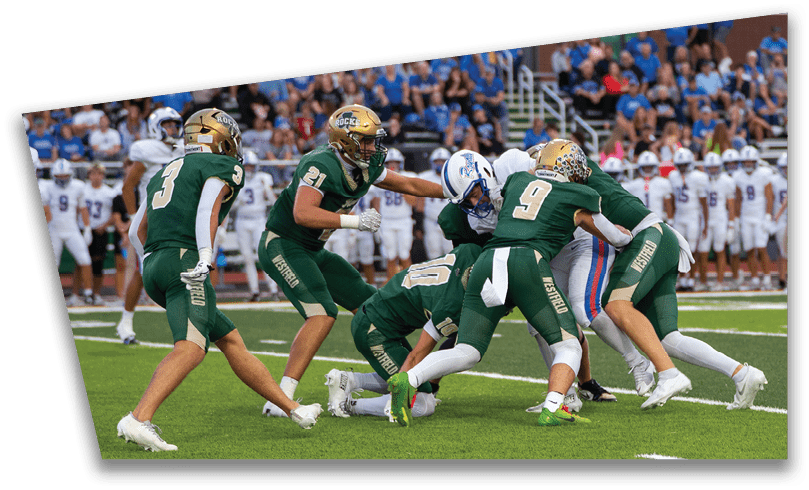 People wearing black American Canyon football uniforms and helmets are standing on a football field at night. Description generated by AI