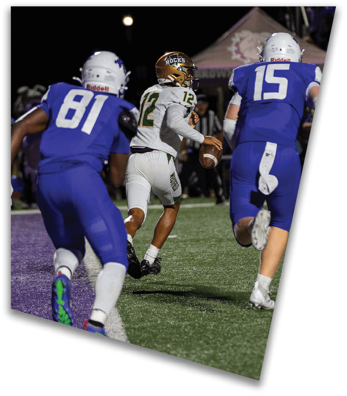 A person wearing a dark football uniform and helmet with “American Canyon" on the jersey is kneeling on one knee on a field at night. Description generated by AI