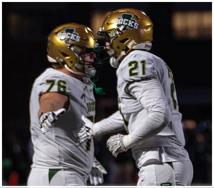A group of football players huddled together on the field. Description generated by AI