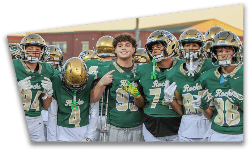 People wearing black American Canyon football uniforms and helmets are standing on a football field at night. Description generated by AI