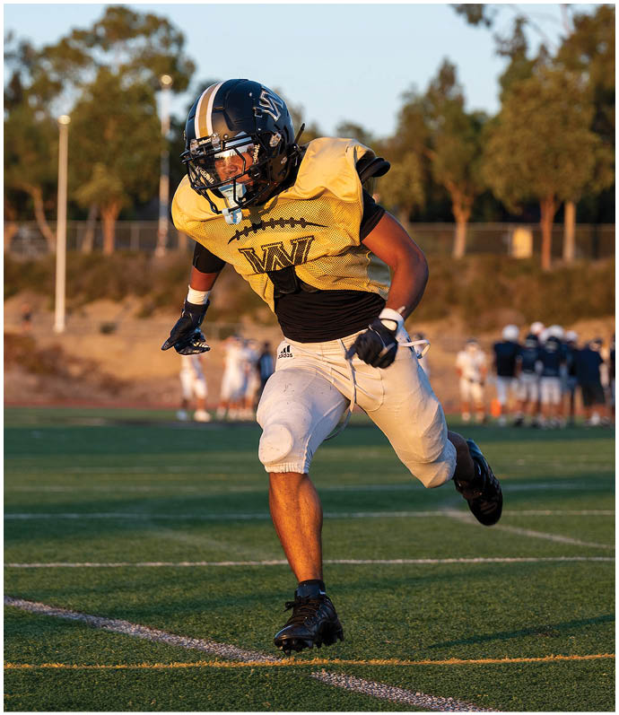 A person wearing white shorts and black cleats is running on a green sports field marked with white and orange lines. Description generated by AI