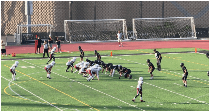 Two men are playing football on a field. One man is tackling the other, who is falling to the ground. AI generated content