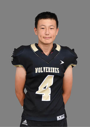 A young man wearing a white and black jersey with the number 14 on it. Description generated by AI