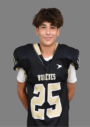 A young man wearing a white and black jersey with the number 14 on it. Description generated by AI