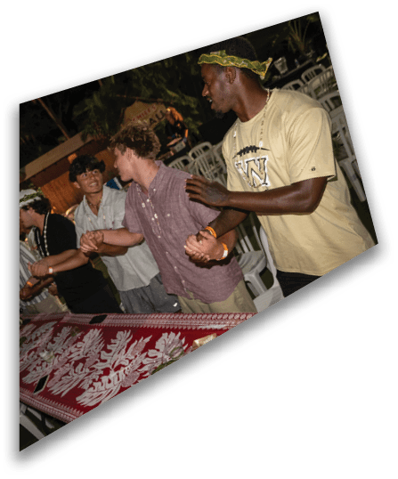 A group of people wearing black football uniforms with helmets are gathered on a field at night, with some of them interacting closely. Description generated by AI