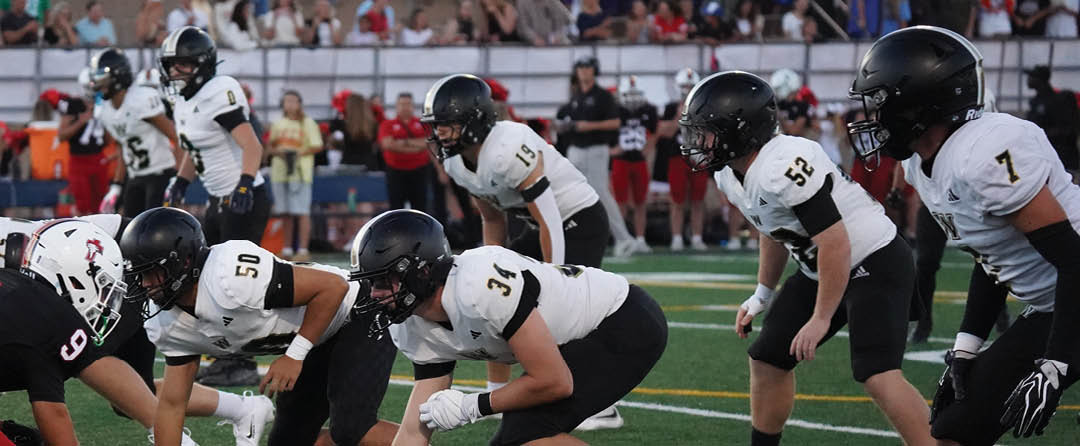 Four people wearing black sports jerseys with “VISTA" on them stand closely together in front of a large crowd, with one person raising an arm in celebration. Description generated by AI