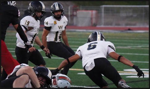 Two men wearing football uniforms are hugging each other on a field. AI generated content