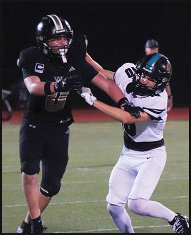 Two men embrace on a field, one wearing a black shirt and the other wearing a black and white shirt. AI generated content