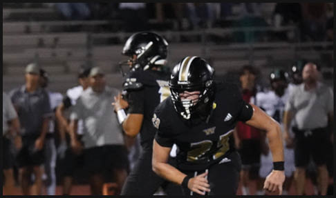 Two men wearing football uniforms are hugging each other on a field. AI generated content