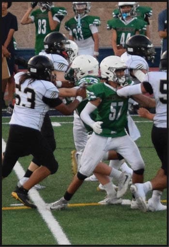 Several people wearing sports uniforms are engaged in a football game on a grassy field near a marked line. Description generated by AI