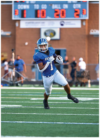 Two football players running on a field. Description generated by AI
