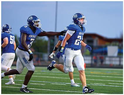 Two football players running on a field. Description generated by AI