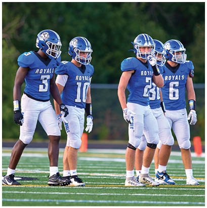A group of football players standing on a field. Description generated by AI