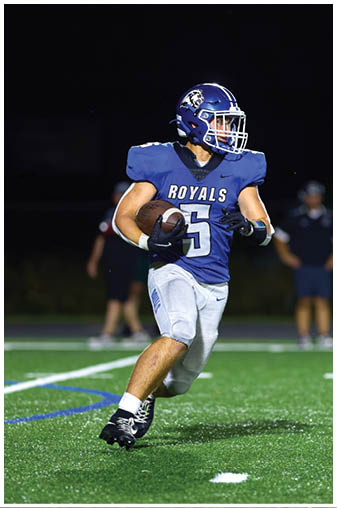 A football player in a blue jersey running on the field. Description generated by AI