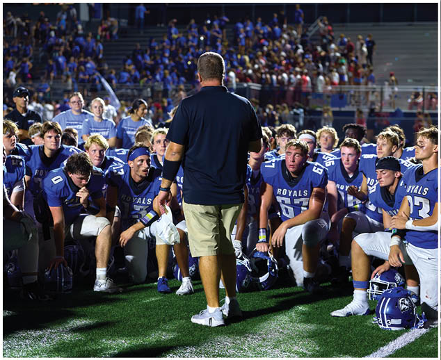 A group of football players sitting on the field. Description generated by AI