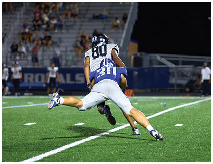A football player is tackled by another player. Description generated by AI
