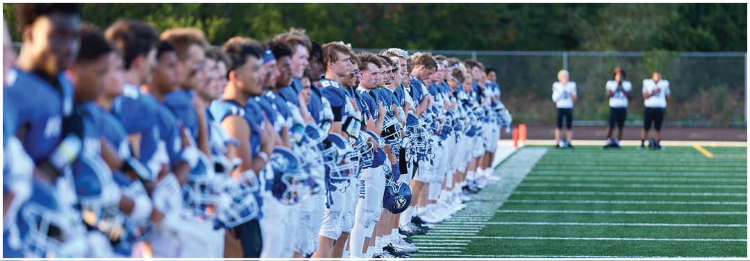 A group of football players standing on a field. Description generated by AI