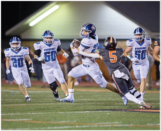 A football player in a blue and white uniform running with a football. Description generated by AI