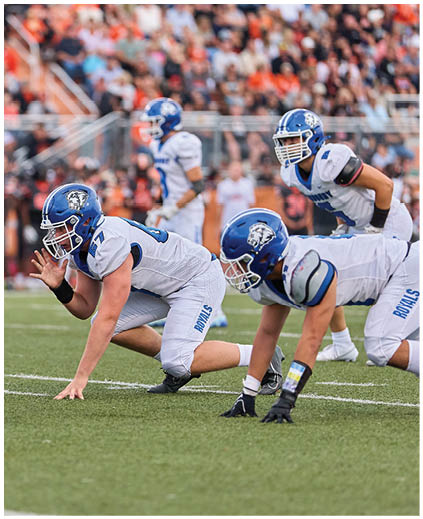 A football game is taking place with a group of men on the field. Description generated by AI
