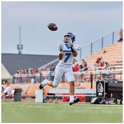 A football player catching a ball in a stadium. Description generated by AI