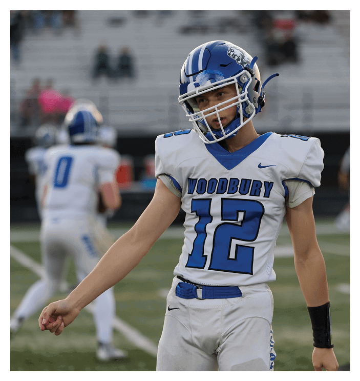 A football game is in progress with players on the field. One player is throwing a football while another player is trying to catch it. The players are wearing uniforms and are actively engaged in the game. AI generated content