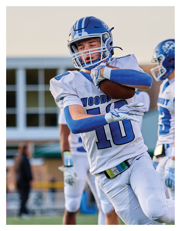 A football player wearing a helmet and white uniform is holding his helmet above his head. AI generated content
