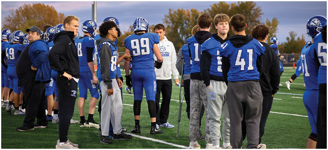Three football players standing on a field. Description generated by AI