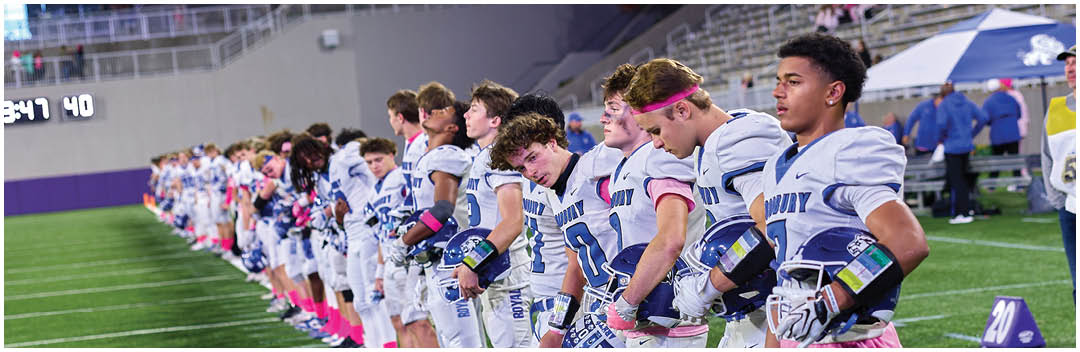 A group of football players standing on a field. Description generated by AI