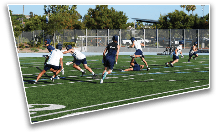 People wearing sports uniforms are actively playing a game on a green outdoor field with white yard lines and a goalpost in the background. Description generated by AI