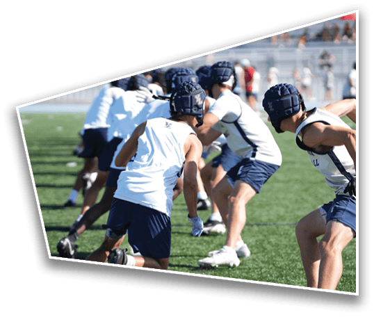 People wearing helmets and athletic clothing are crouched and appear to be preparing for a sports drill on a grassy field. Description generated by AI