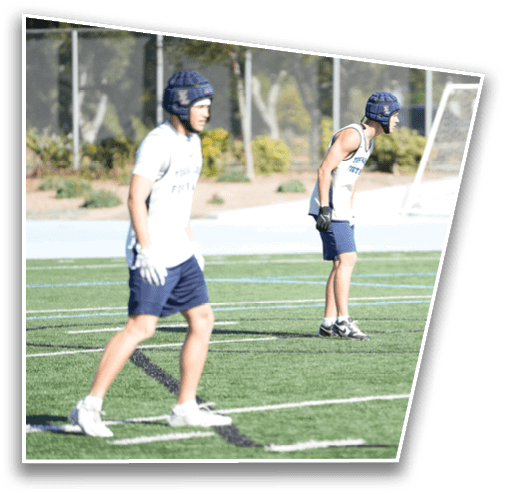 A person wearing a sports jersey, shorts, gloves, and athletic shoes is standing on a green artificial turf field near a soccer goal. Description generated by AI