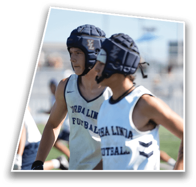 Two people wearing sports helmets and sleeveless jerseys with the text “TORBA LINIA FOOTBALL" are standing outdoors. Description generated by AI